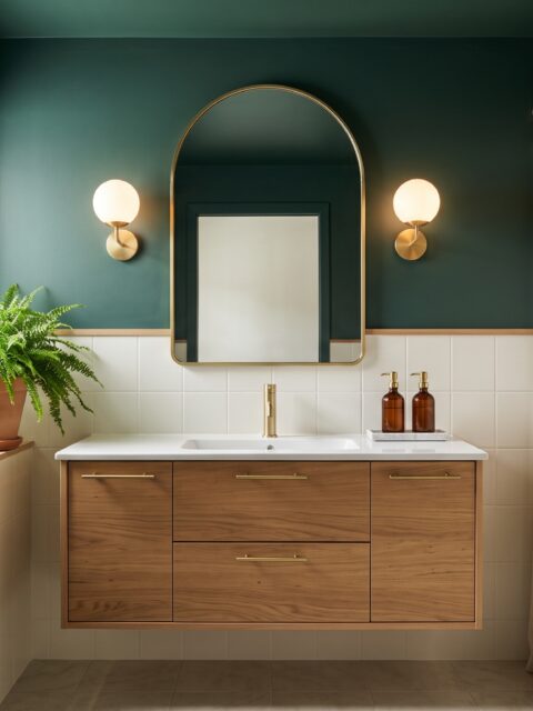Baño pequeño moderno con paredes verde petróleo, mueble de roble suspendido, espejo arqueado y apliques encendidos